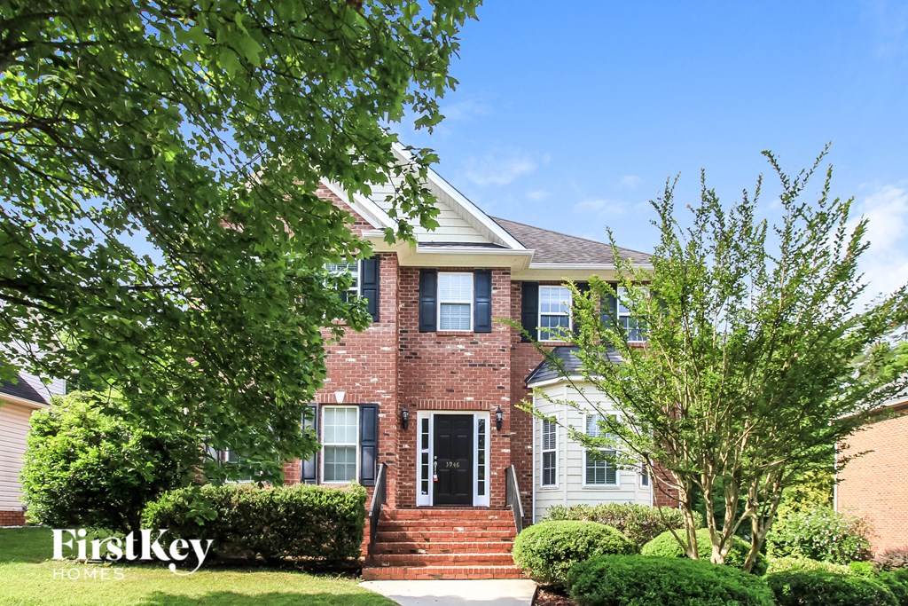 a brick house with trees and bushes in front of it