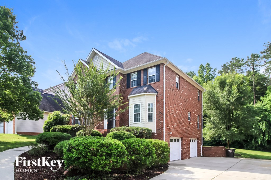 front view of a brick house with white shutters and a driveway
