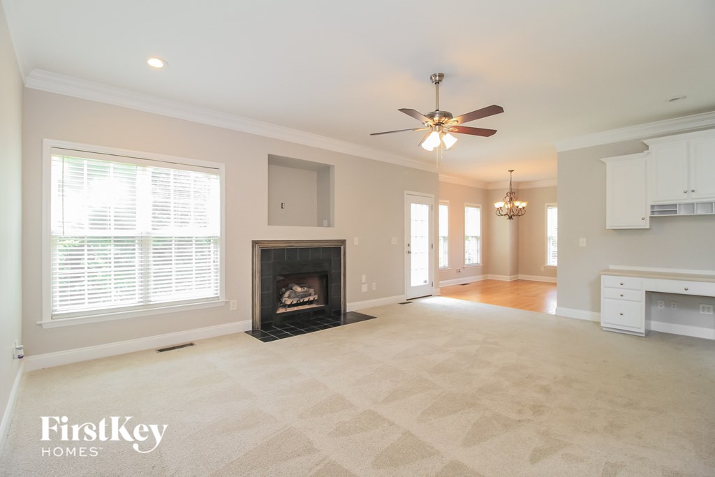 an empty living room with a fireplace and a ceiling fan