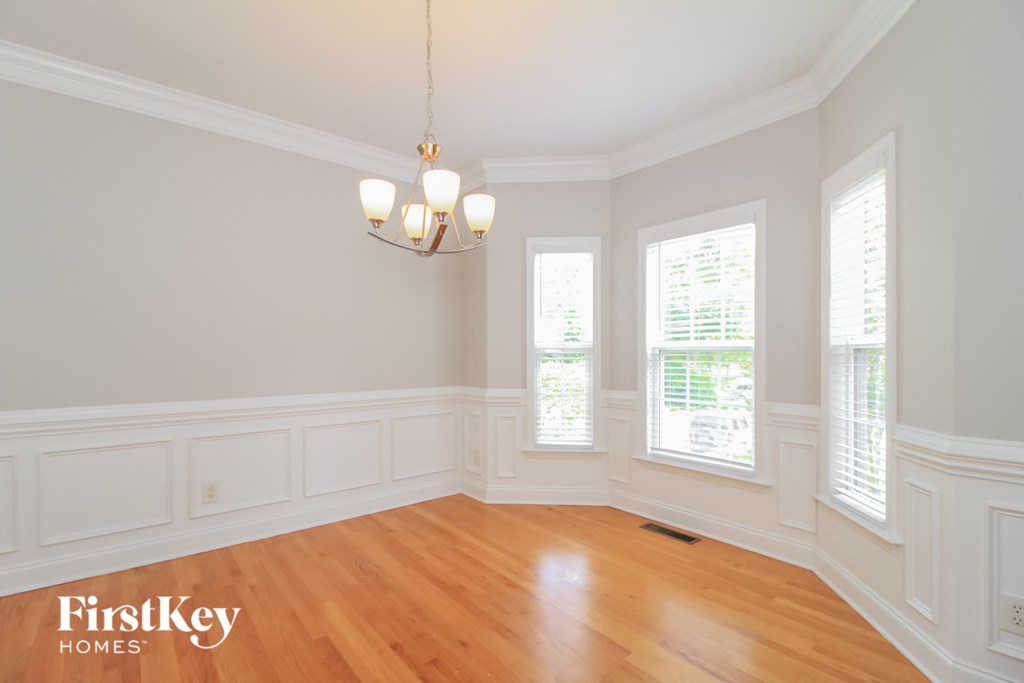 an empty dining room with a chandelier and three windows