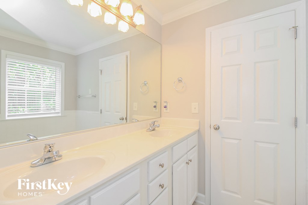 a white bathroom with a large mirror and a white sink