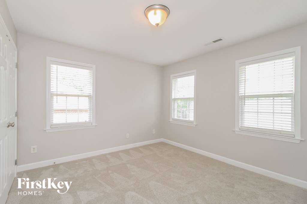a spacious room with three windows and a ceiling light