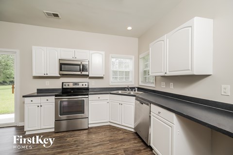 A kitchen with white cabinets and a black countertop.