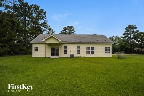 A house with a green lawn and trees in the background.