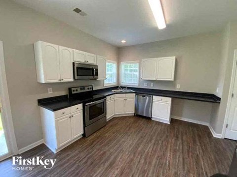 A kitchen with white cabinets and black countertops.