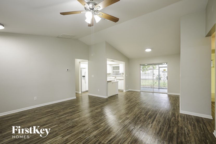 A spacious room with a ceiling fan and wooden flooring.