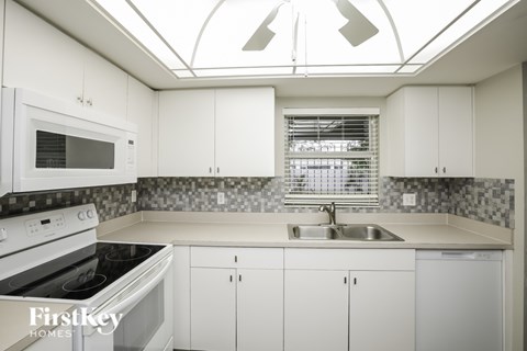 A kitchen with white cabinets and a black and white checkered backsplash.