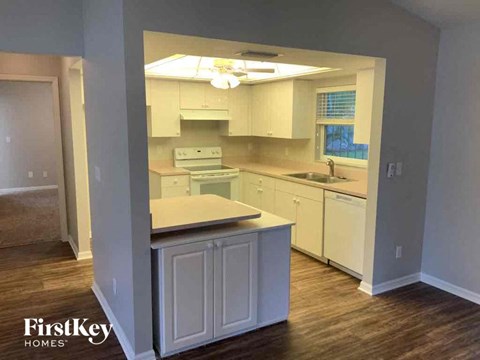 A kitchen with white cabinets and a wooden floor.