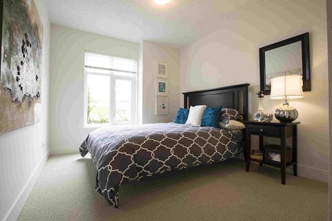 a bedroom with a bed and a table with a lamp #victoria #rentals #affordable #apartments #bed