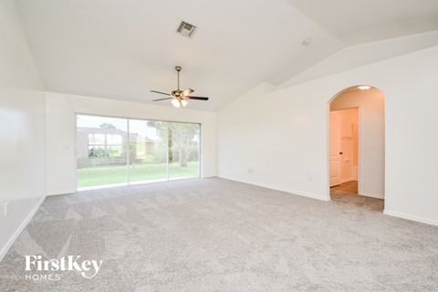 A spacious room with a ceiling fan and a carpeted floor.