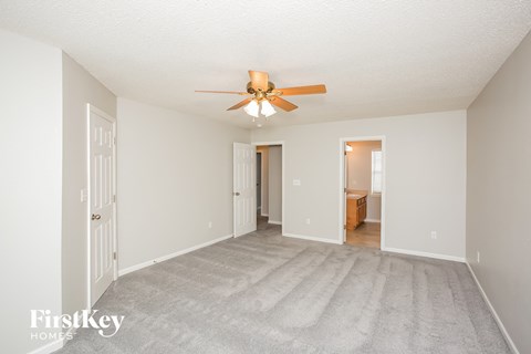 a spacious living room with carpet and a ceiling fan