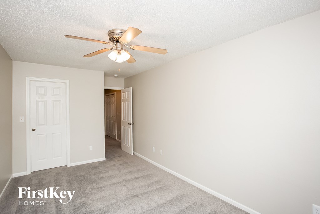 a bedroom with a ceiling fan and a door to a closet