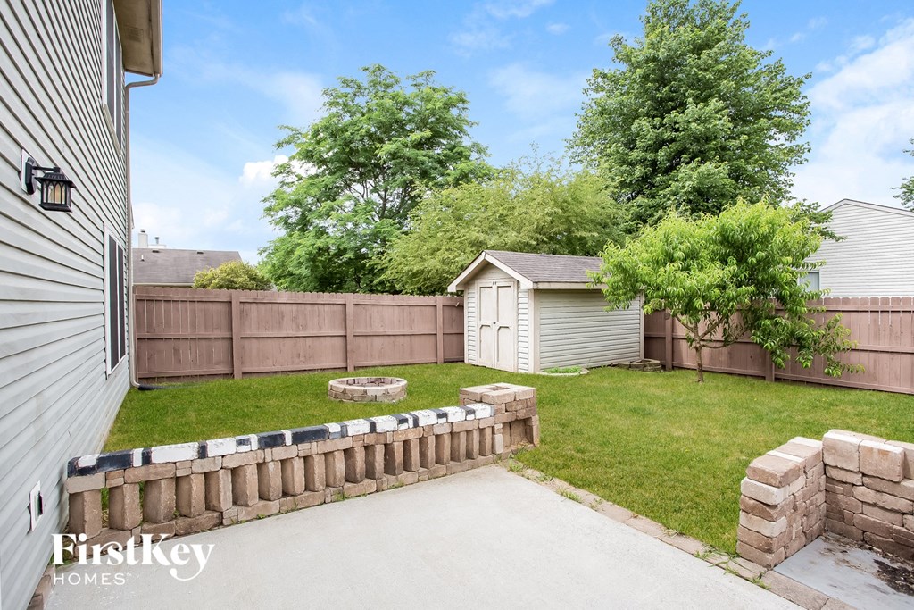 a backyard with a fence and a shed and a lawn