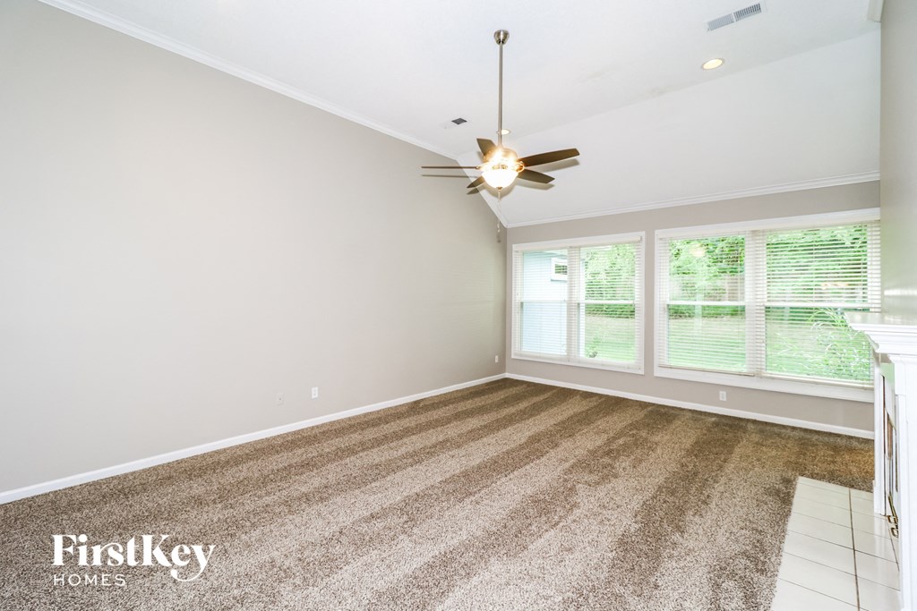 A room with a ceiling fan and a carpet on the floor.