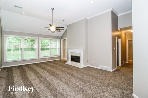 A spacious living room with a fireplace and a ceiling fan.
