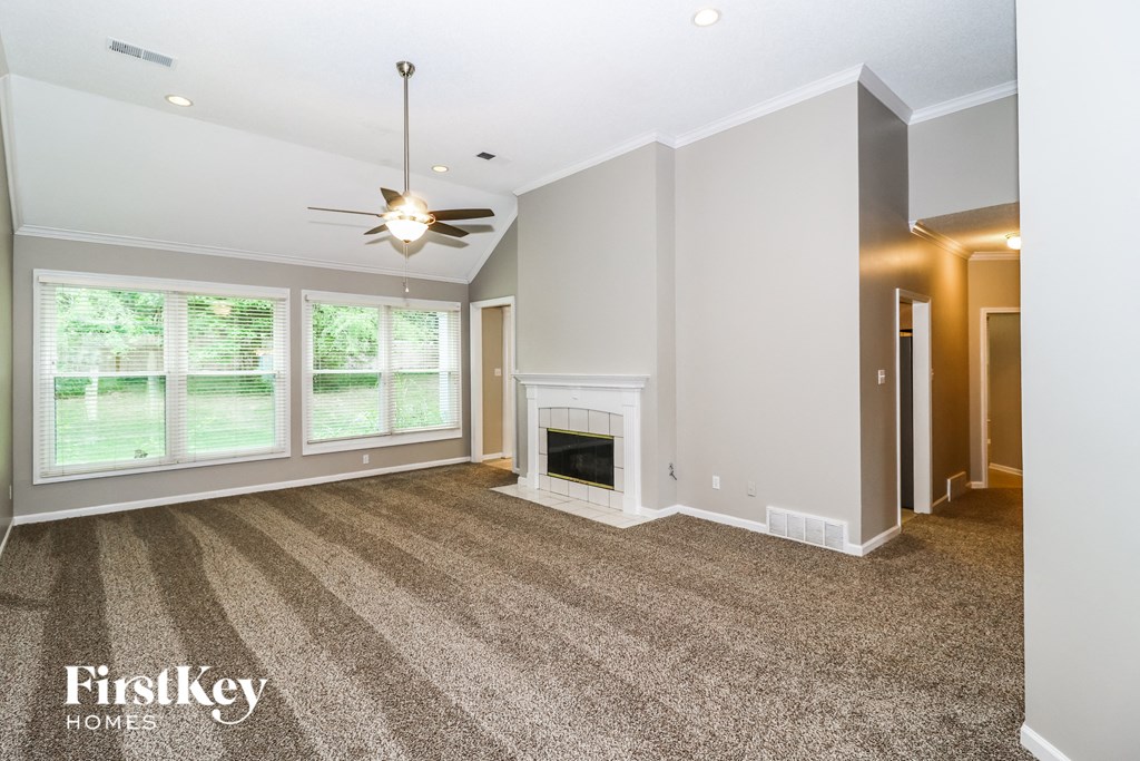 A spacious living room with a fireplace and a ceiling fan.