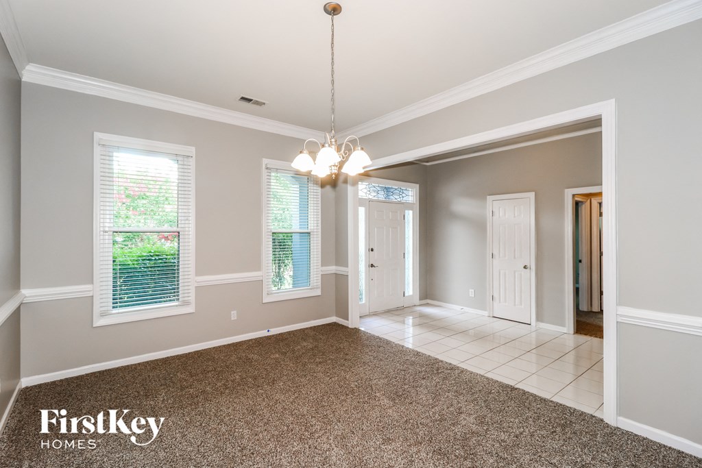 A spacious room with a chandelier and a carpeted floor.