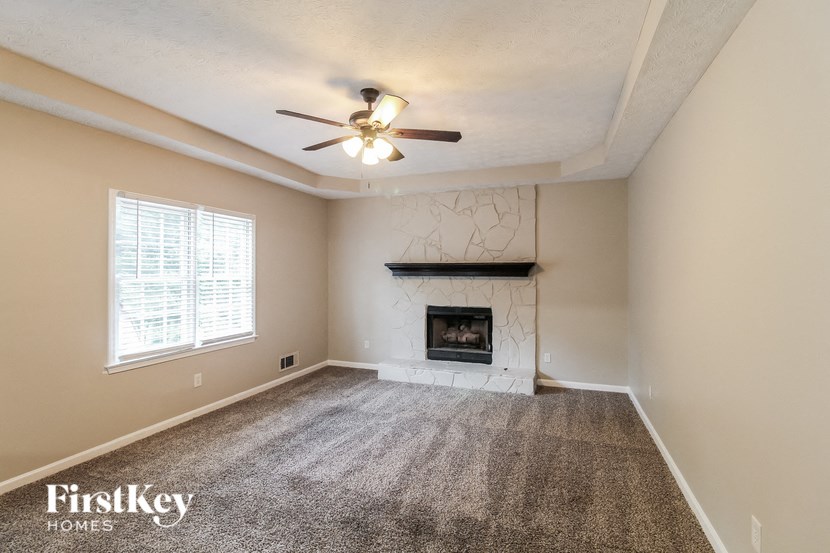 an empty living room with a fireplace and a ceiling fan