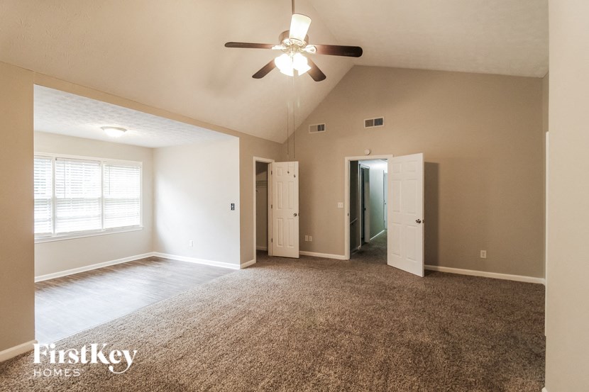 an empty living room with a ceiling fan and a window