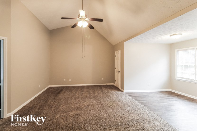 the spacious living room with carpet and ceiling fan
