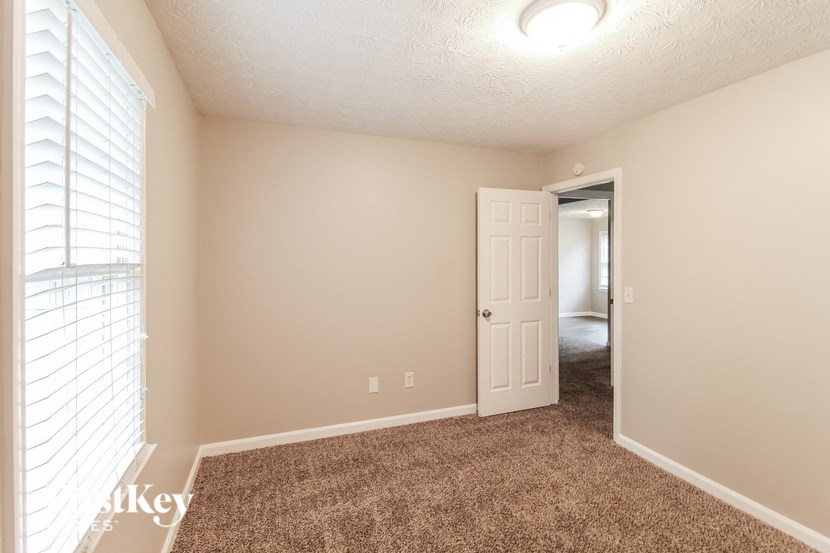 a room with a carpeted floor and a door to a hallway