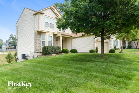 a home with a lawn and a tree in front of it