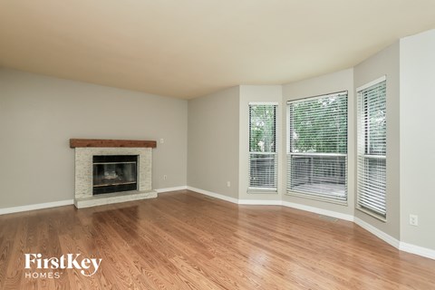 a living room with a fireplace and wooden floors and windows