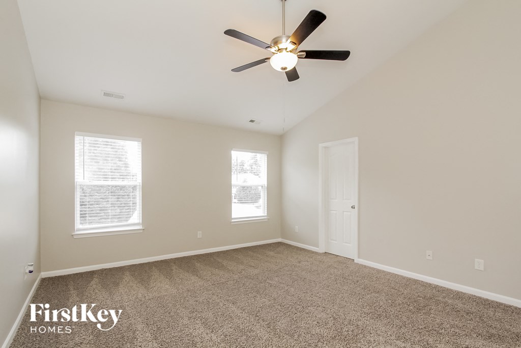 a spacious living room with carpet and a ceiling fan