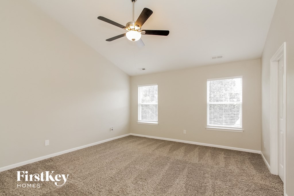 a spacious living room with carpet and a ceiling fan