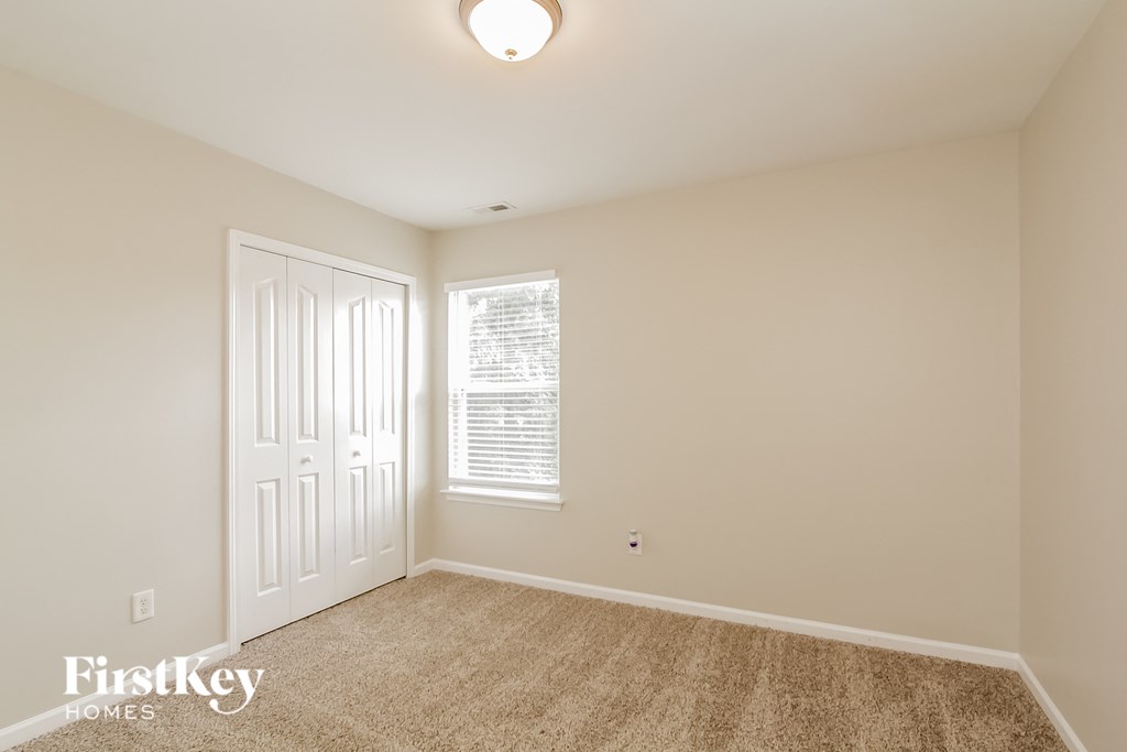 a bedroom with carpet and a white door and a window