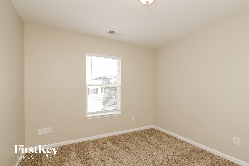 a bedroom with beige carpet and a window