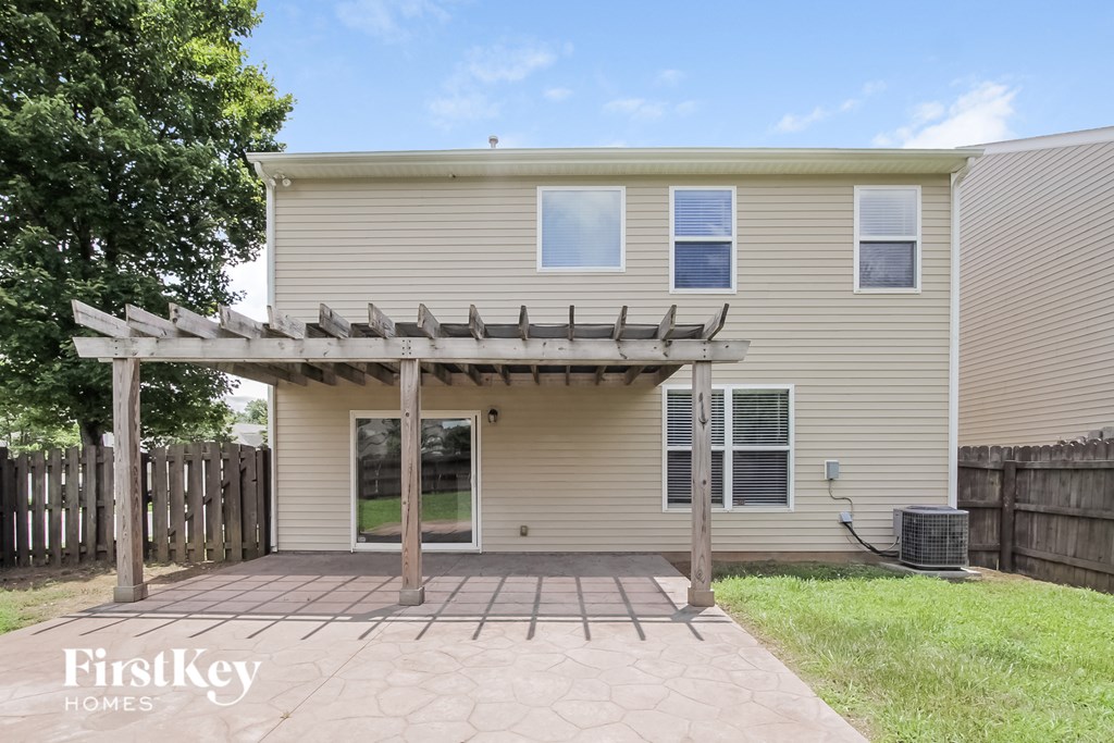 a backyard patio with a house with a pergola