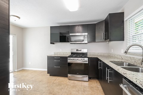 A kitchen with black cabinets and a stainless steel oven.