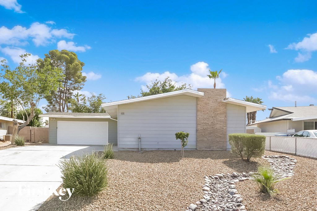 a white house with a gravel driveway and a palm tree