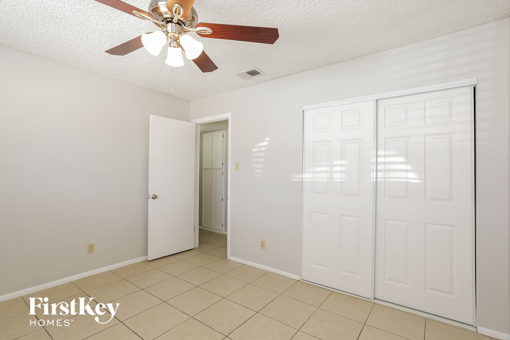 a bedroom with a ceiling fan and a door to a closet