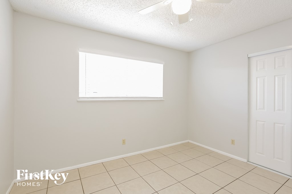 an empty living room with a window and a tile floor