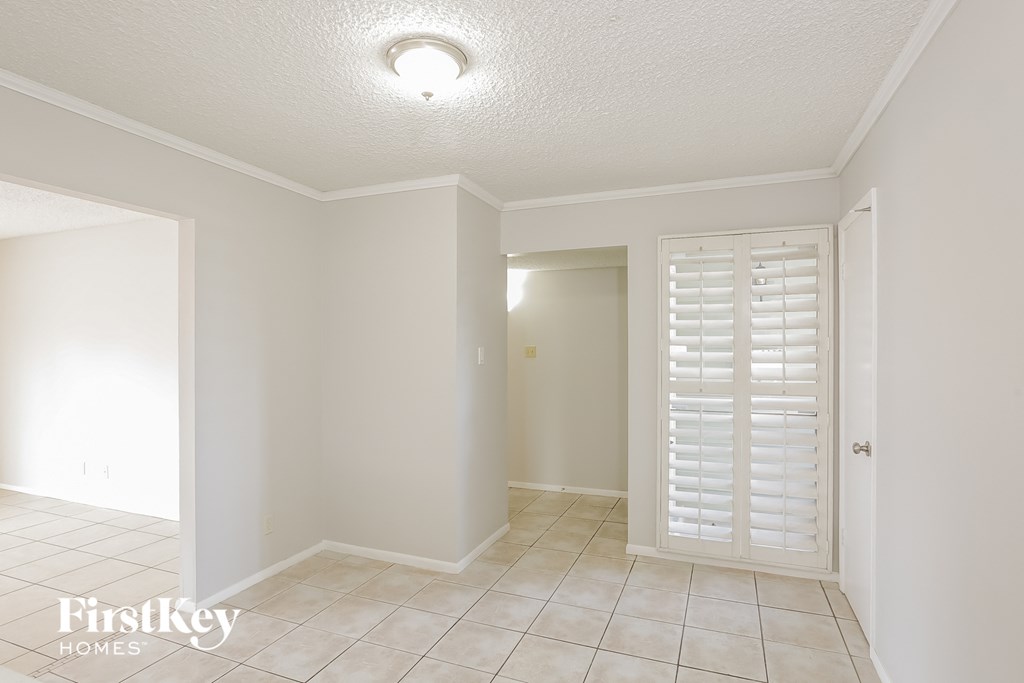 an empty living room with white shutters and a door to a closet