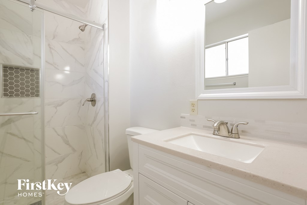 a white bathroom with a shower toilet and sink