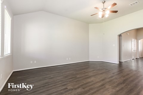 A spacious room with wooden floors and a ceiling fan.
