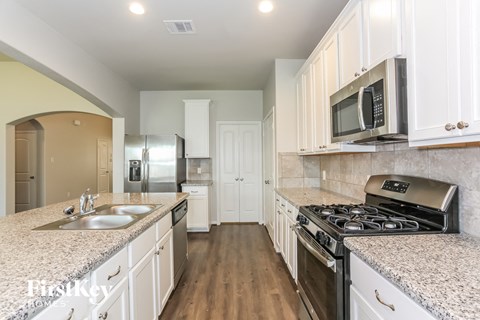 A kitchen with white cabinets and a granite countertop.
