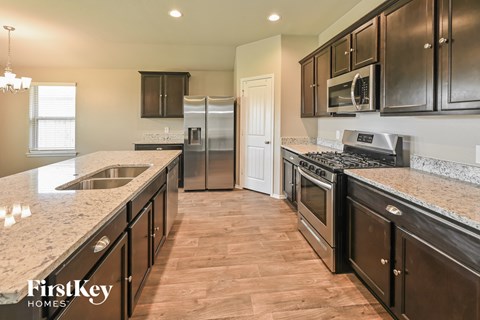 A kitchen with dark wood cabinets and granite countertops.