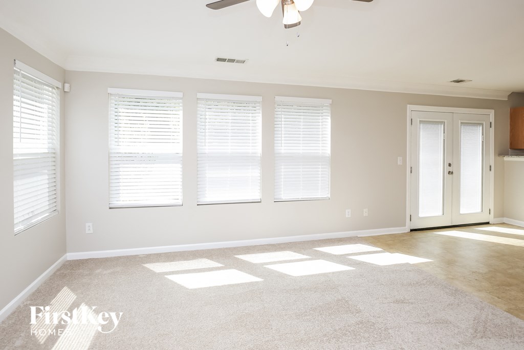 a living room with three windows and a white door
