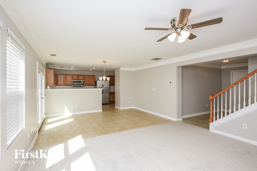 an empty living room and kitchen with a ceiling fan