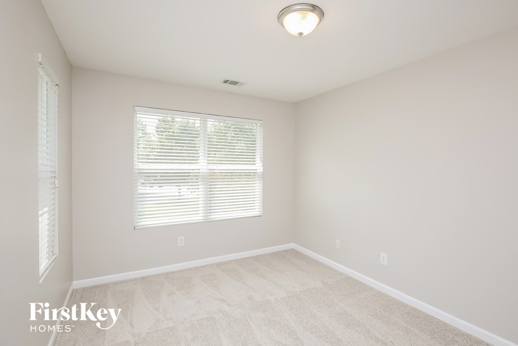a bedroom with a large window and a carpeted floor