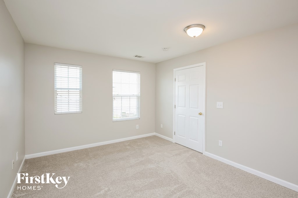 a bedroom with white walls and a white door and window
