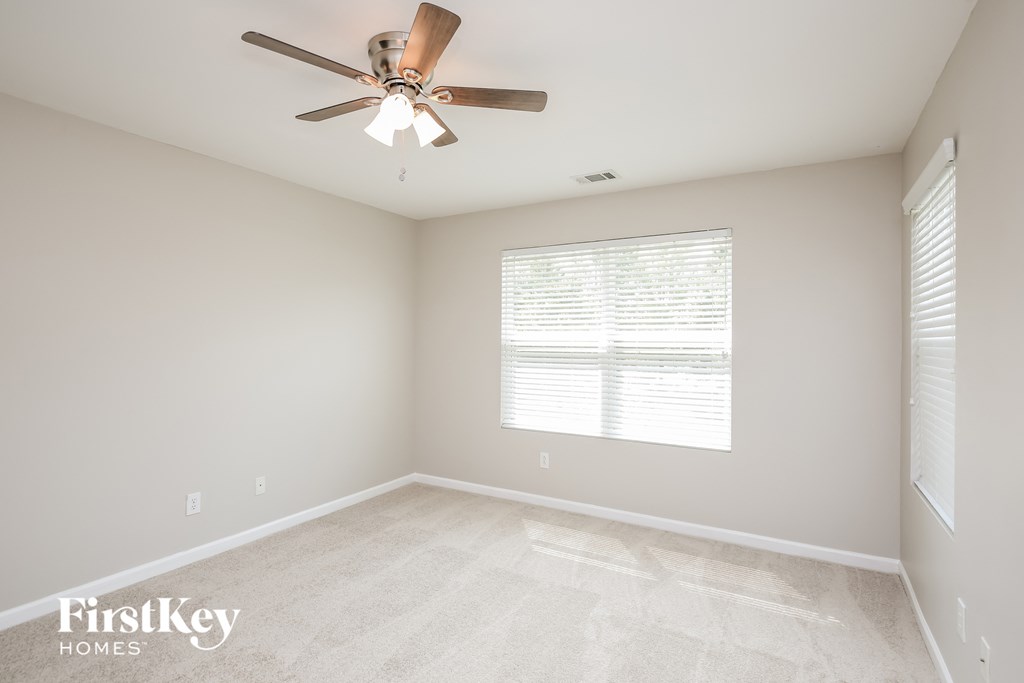 an empty room with a ceiling fan and a window