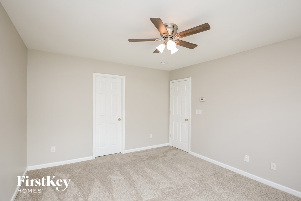 a empty living room with a ceiling fan and two doors