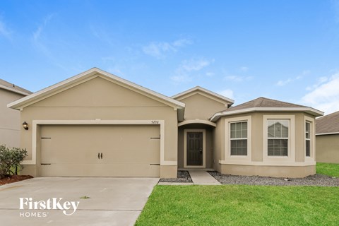 a beige house with a driveway and a lawn