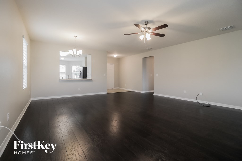an empty living room with wood floors and a ceiling fan