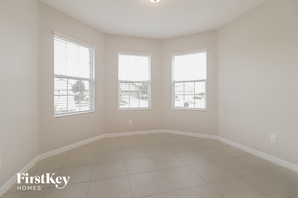 an empty living room with three windows and a tiled floor